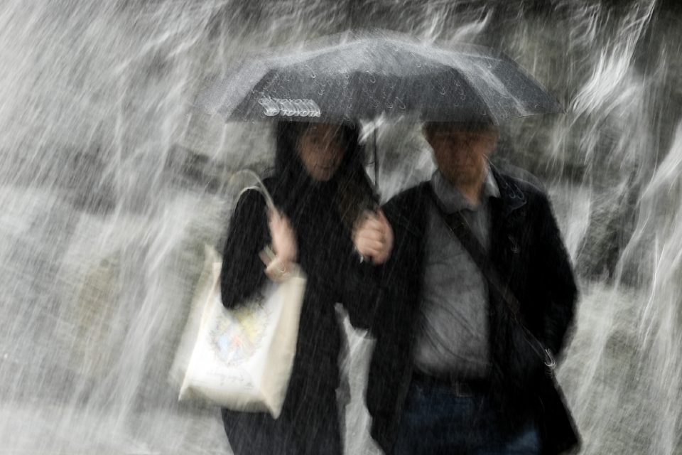 A couple protects themselves with an umbrella while walking under heavy rain in Moscow's Alexander Garden on May 29, 2017. / AFP PHOTO / Kirill KUDRYAVTSEV