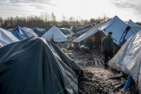 A migrant walks on mud at the Grande Synthe migrant camp near Dunkerque in northern France on December 23, 2015. More than 2,000 migrants, mostly Iraqis and Kurds, live in the camp. The UN refugee agency and the International Organization for Migration (IOM) said this week more than one million migrants and refugees reached Europe this year, most of them by sea, more than four times the figure for 2014.   / AFP PHOTO / DENIS CHARLET