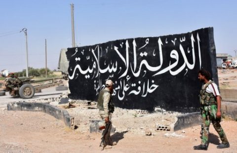 Syrian pro-government forces set up a road checkpoint next to a mural reading the Arabic: "Islamic State" after they took control of the northern Syrian town of Maskanah from the jihadists on June 5, 2017. / AFP PHOTO / George OURFALIAN